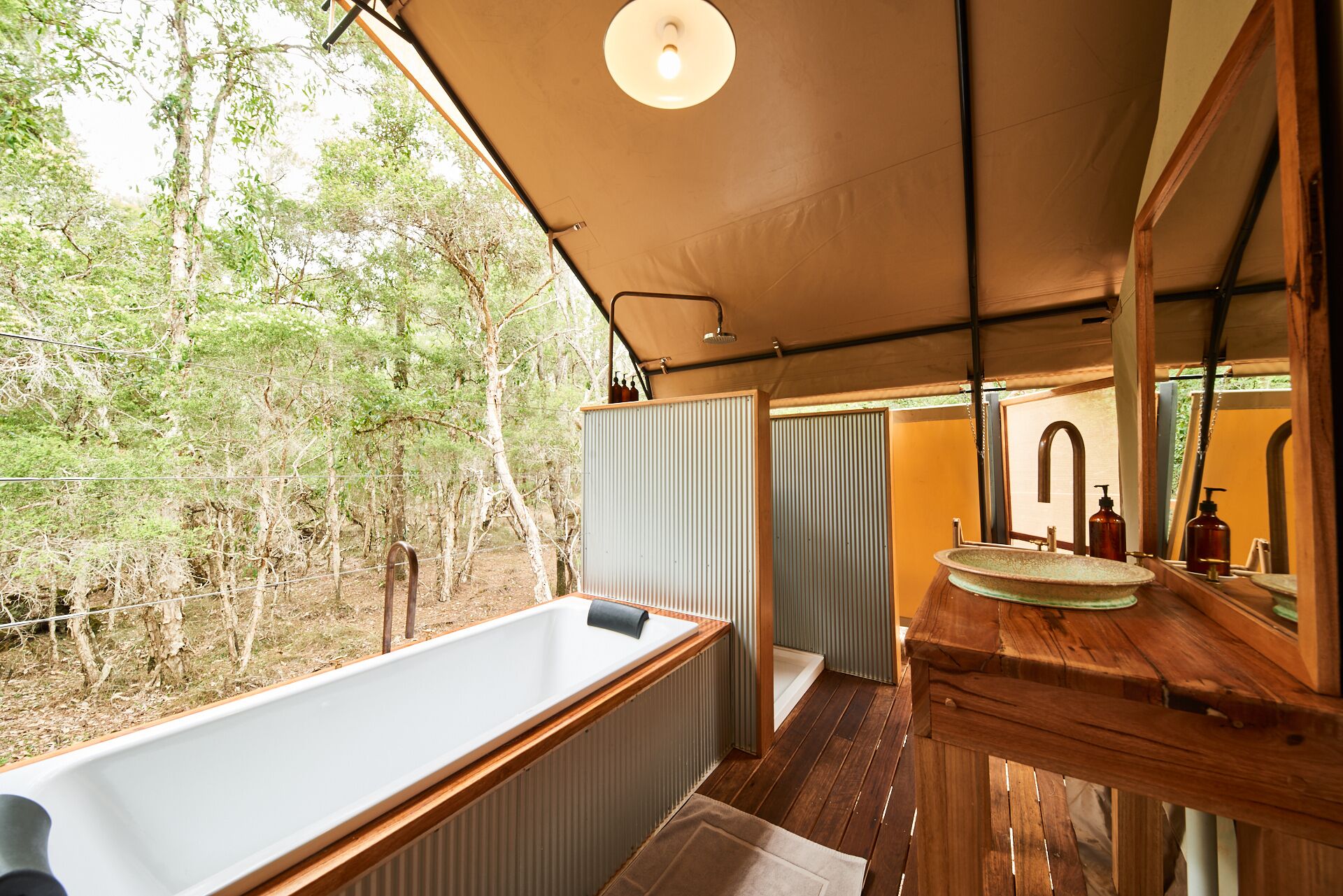 Un baño con un tocador de madera, una bañera y un espejo grande.