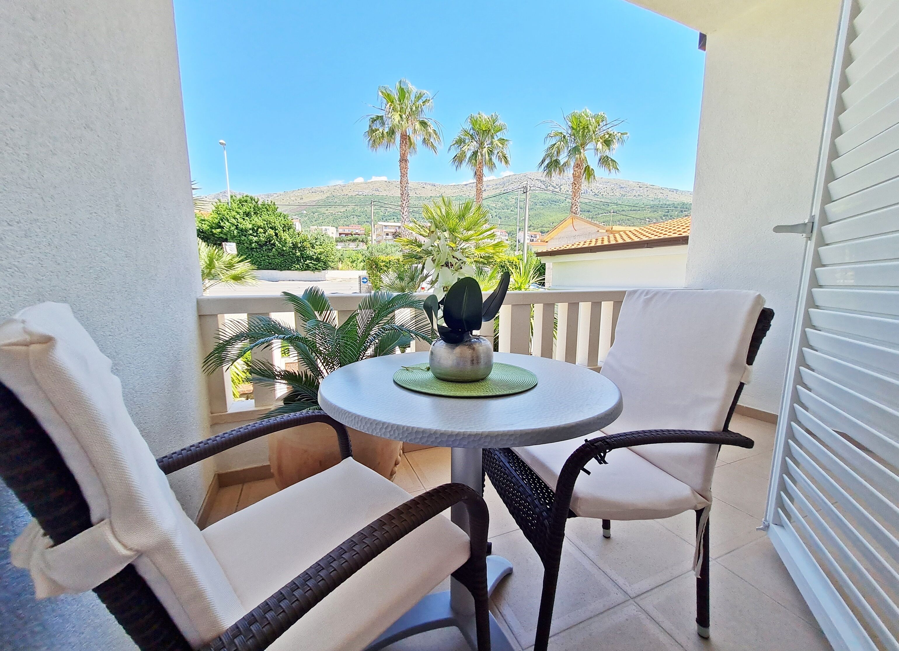 Ein Balkon mit zwei Stühlen, einem kleinen runden Tisch und einem Blumentopf.