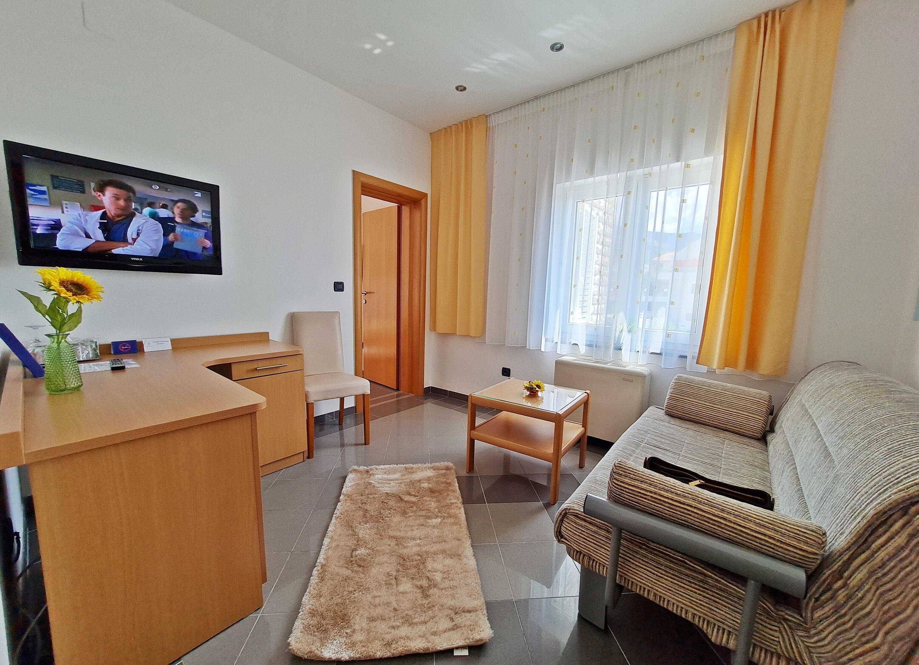 A modern living room with a sofa, a coffee table, a TV, and a wooden desk.