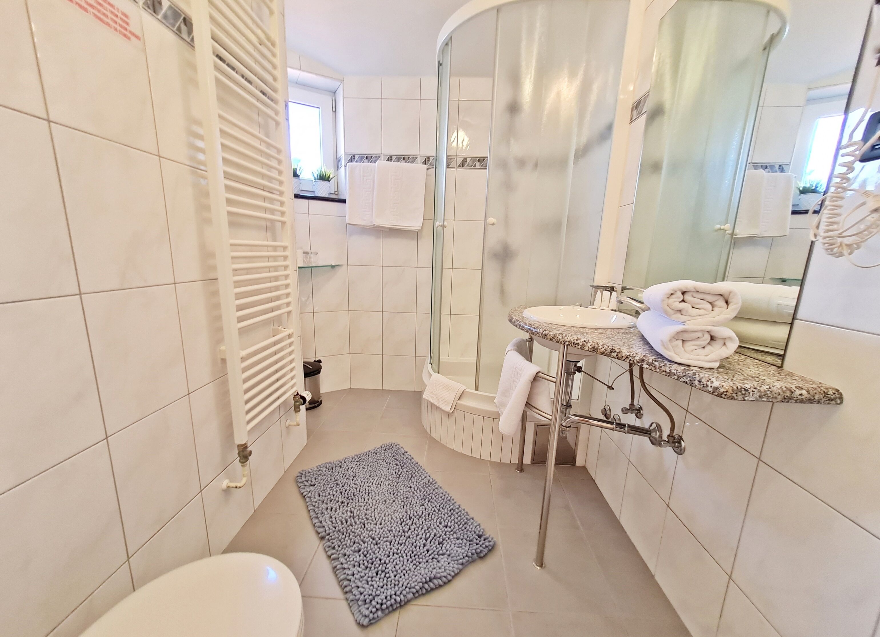 Een moderne badkamer met douche, toilet en wastafel.