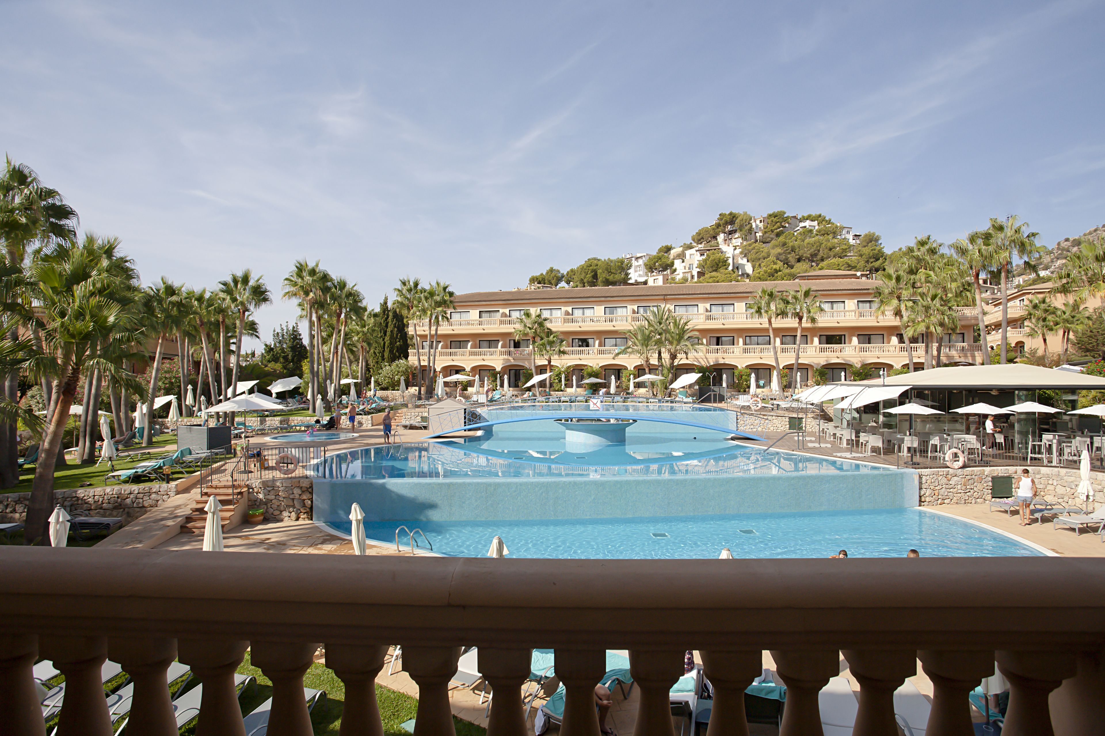Ein Hotel mit großem Pool, Palmen und Blick auf die umliegende Landschaft.