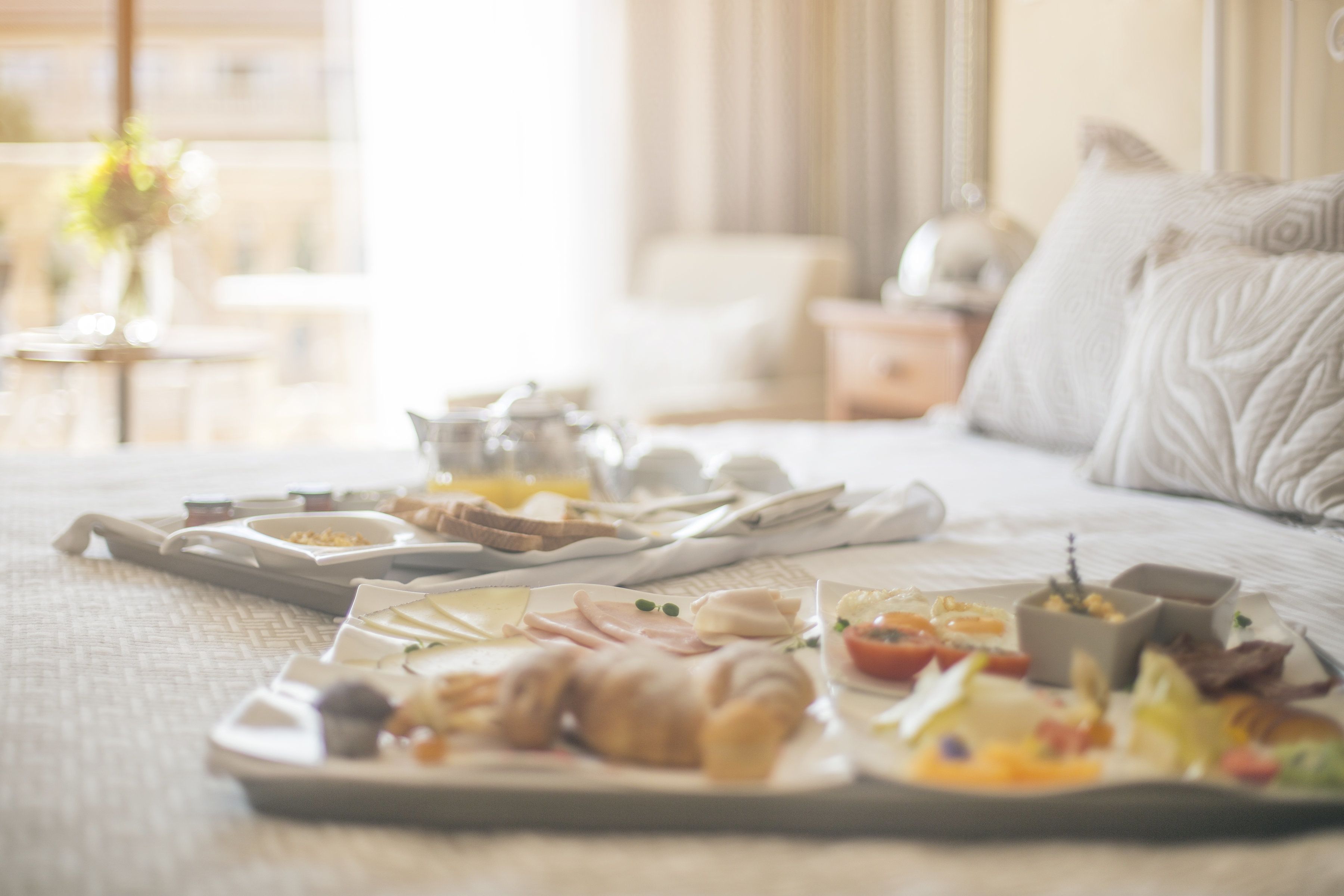 Un plateau de petit-déjeuner avec divers aliments, posé sur un lit dans une chambre d’hôtel.