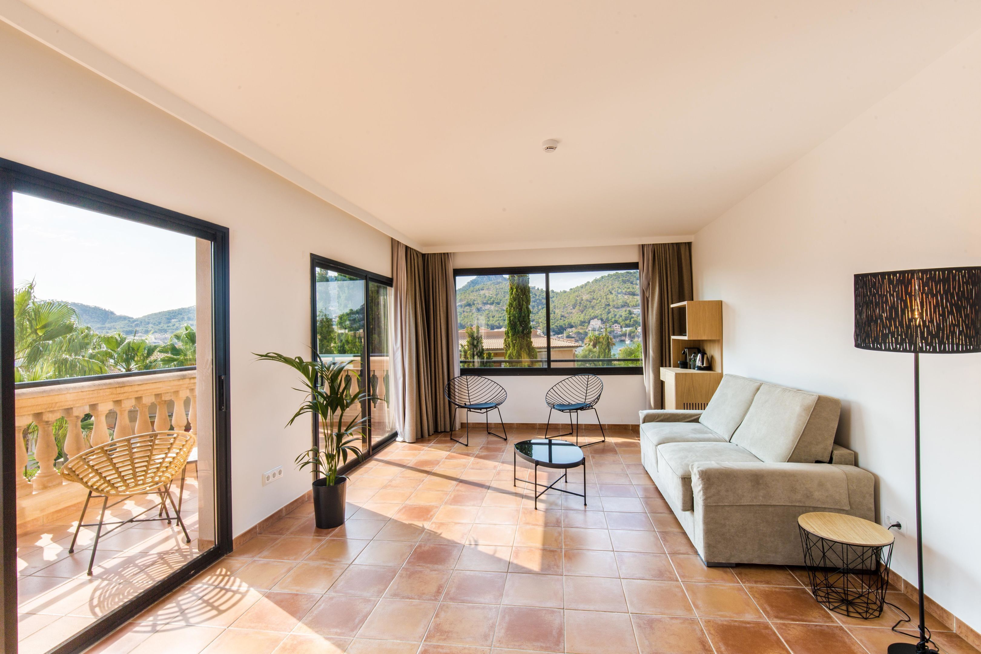 A modern living room with a balcony, a sofa, two chairs, a small table, and a floor lamp.