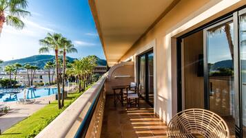 A balcony with a pool view, outdoor furniture, and a chair.