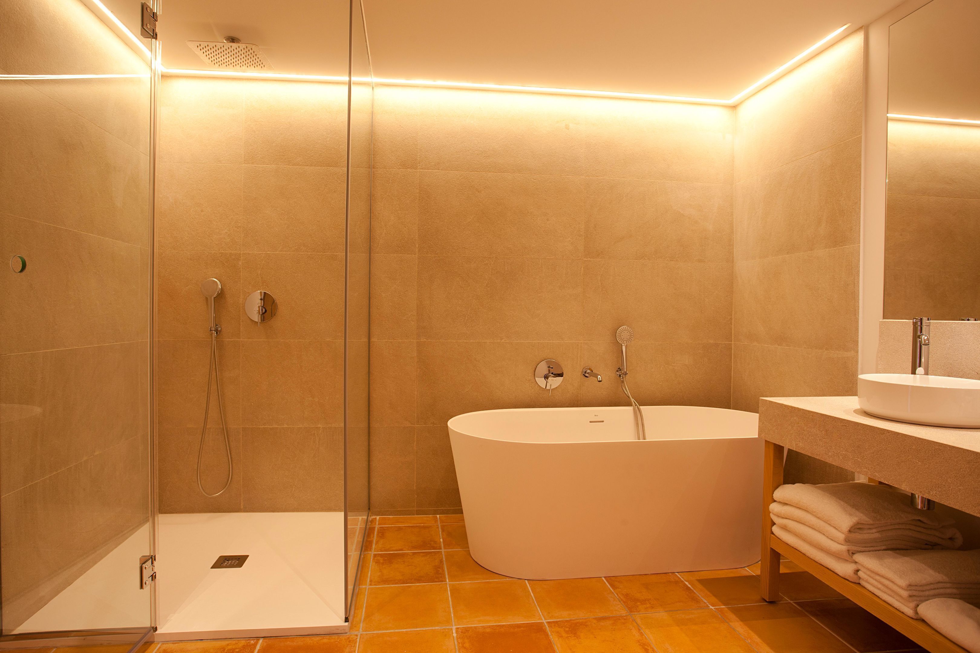 A modern bathroom with a glass shower enclosure, a freestanding bathtub, and a vanity with a mirror.