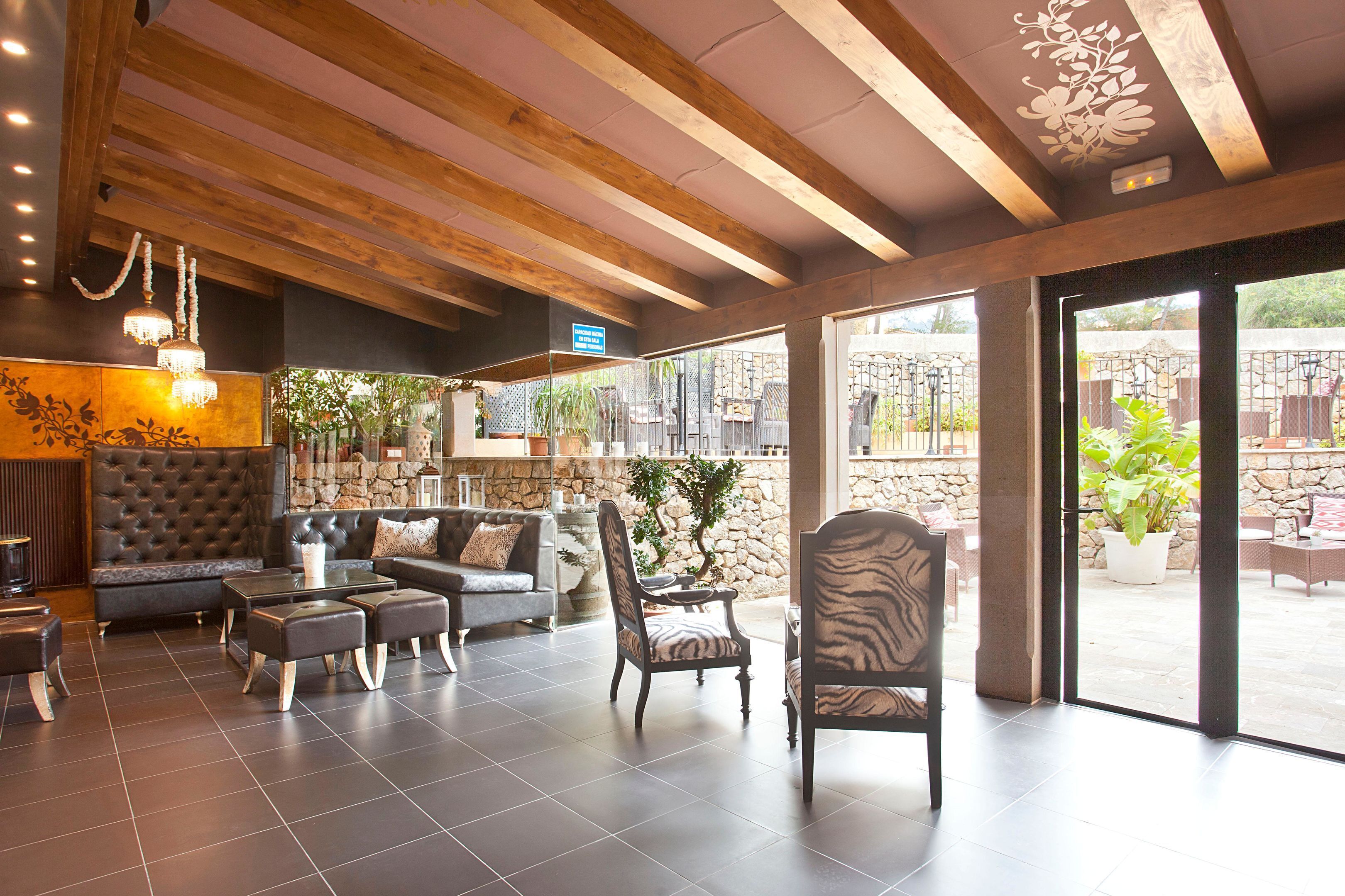 Eine geräumige Lobby mit einer Steinwand, einer großen, gepolsterten Sitzecke und Blick auf die Terrasse.