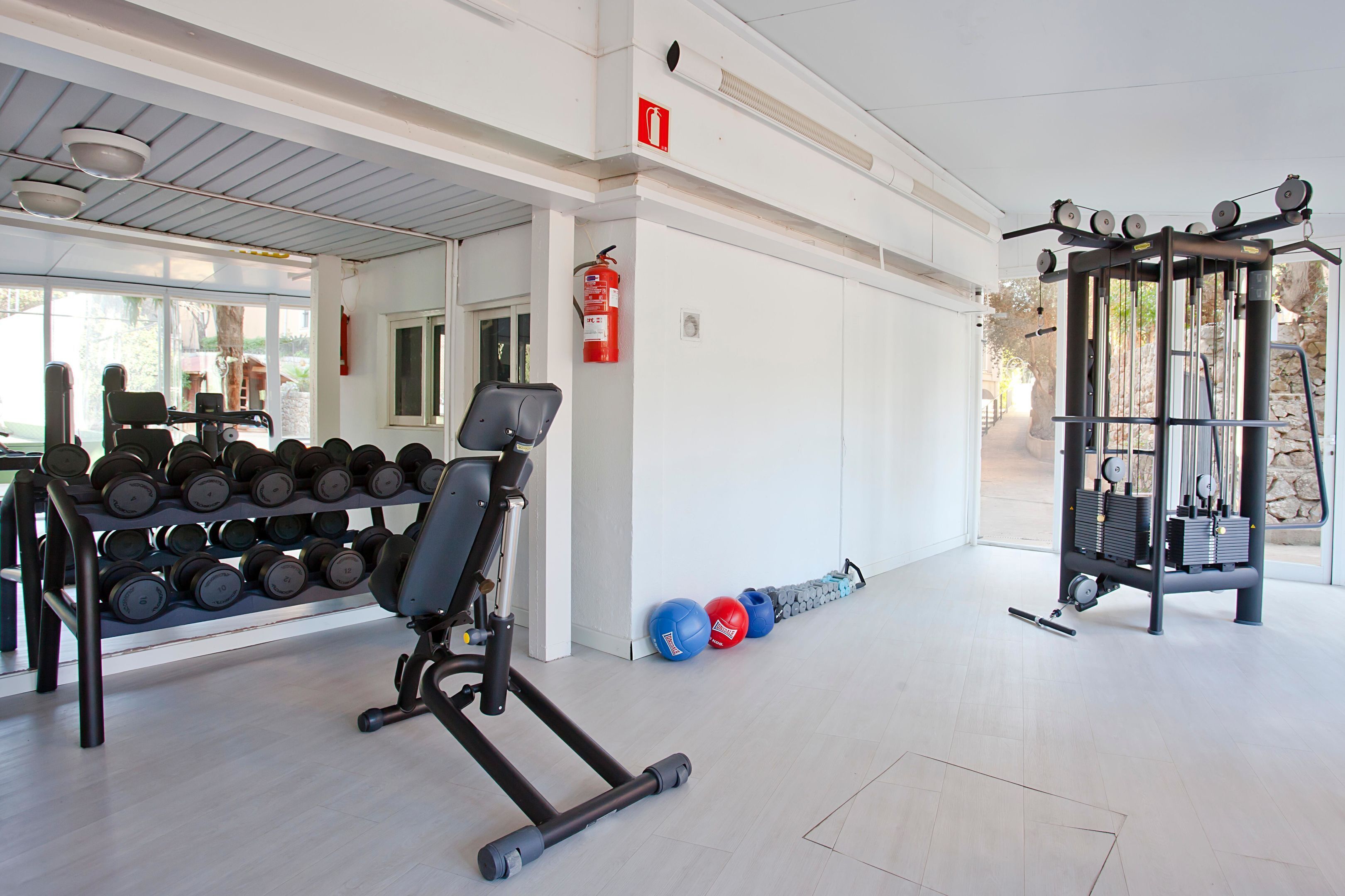 Uma academia com equipamentos de ginástica, halteres e bolas de exercício.