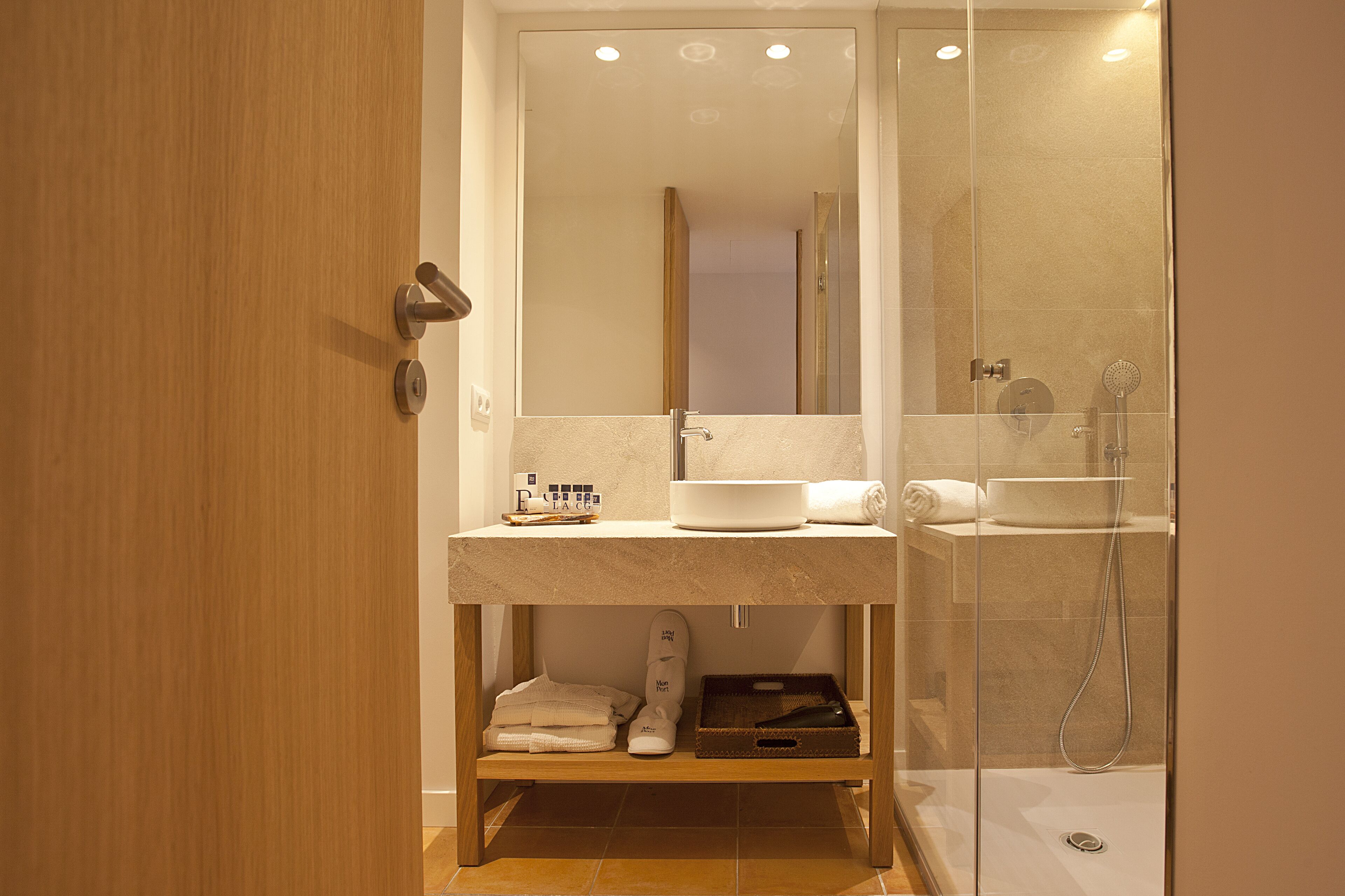 Un baño moderno con cabina de ducha de vidrio, tocador de madera y espejo.