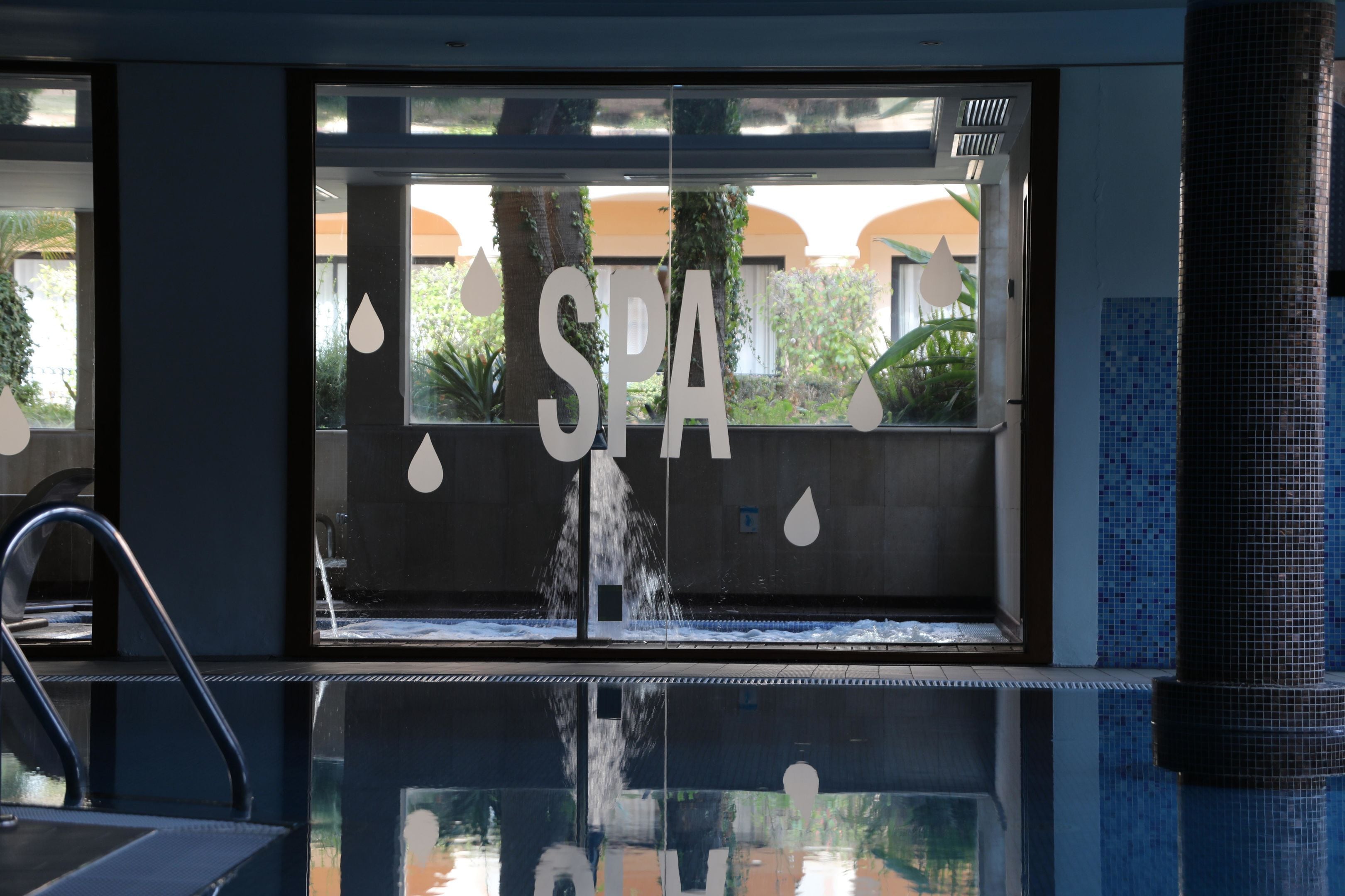 A spa entrance with a water feature, a sign reading 'SPA', and a reflection in the glass.