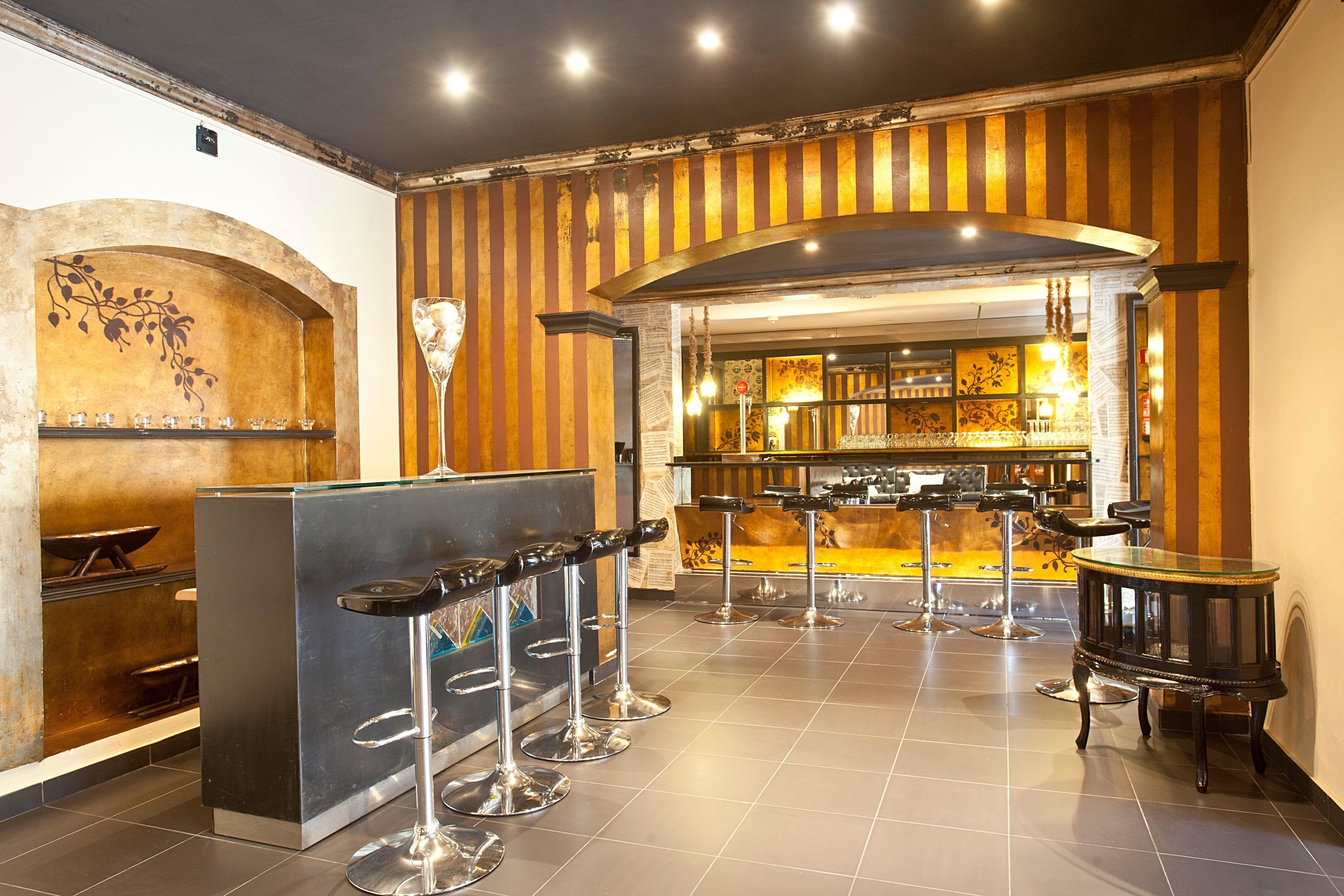 A bar area with stools, a counter, and a decorative wall.