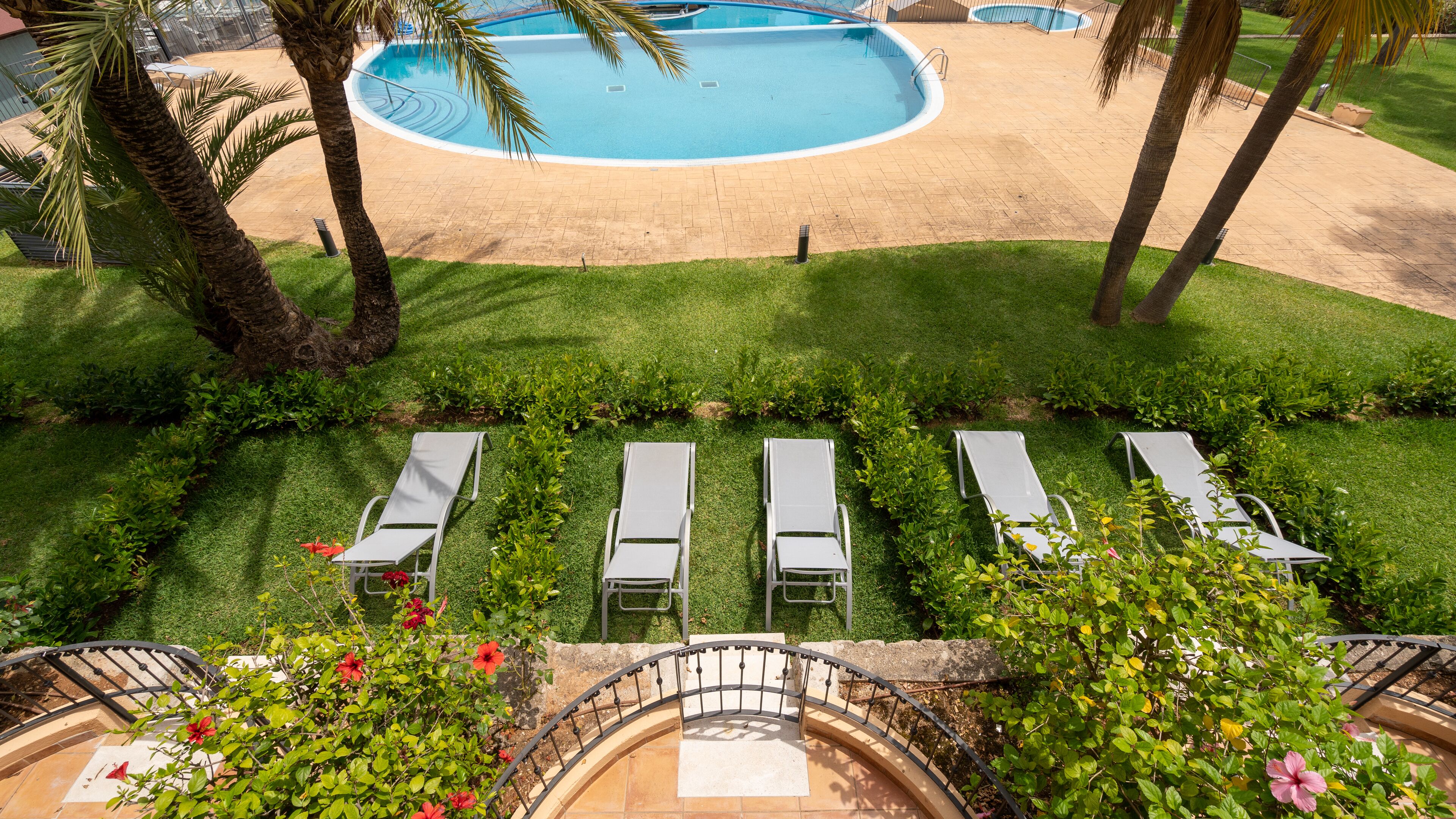 A pool area with lounge chairs and a well-maintained lawn.