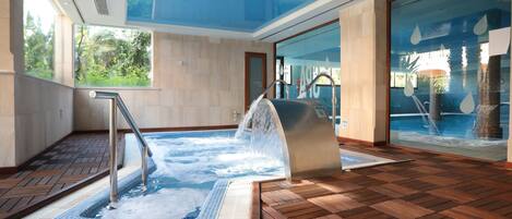 A hot tub area with a wooden floor, a glass wall, and a view of greenery outside.