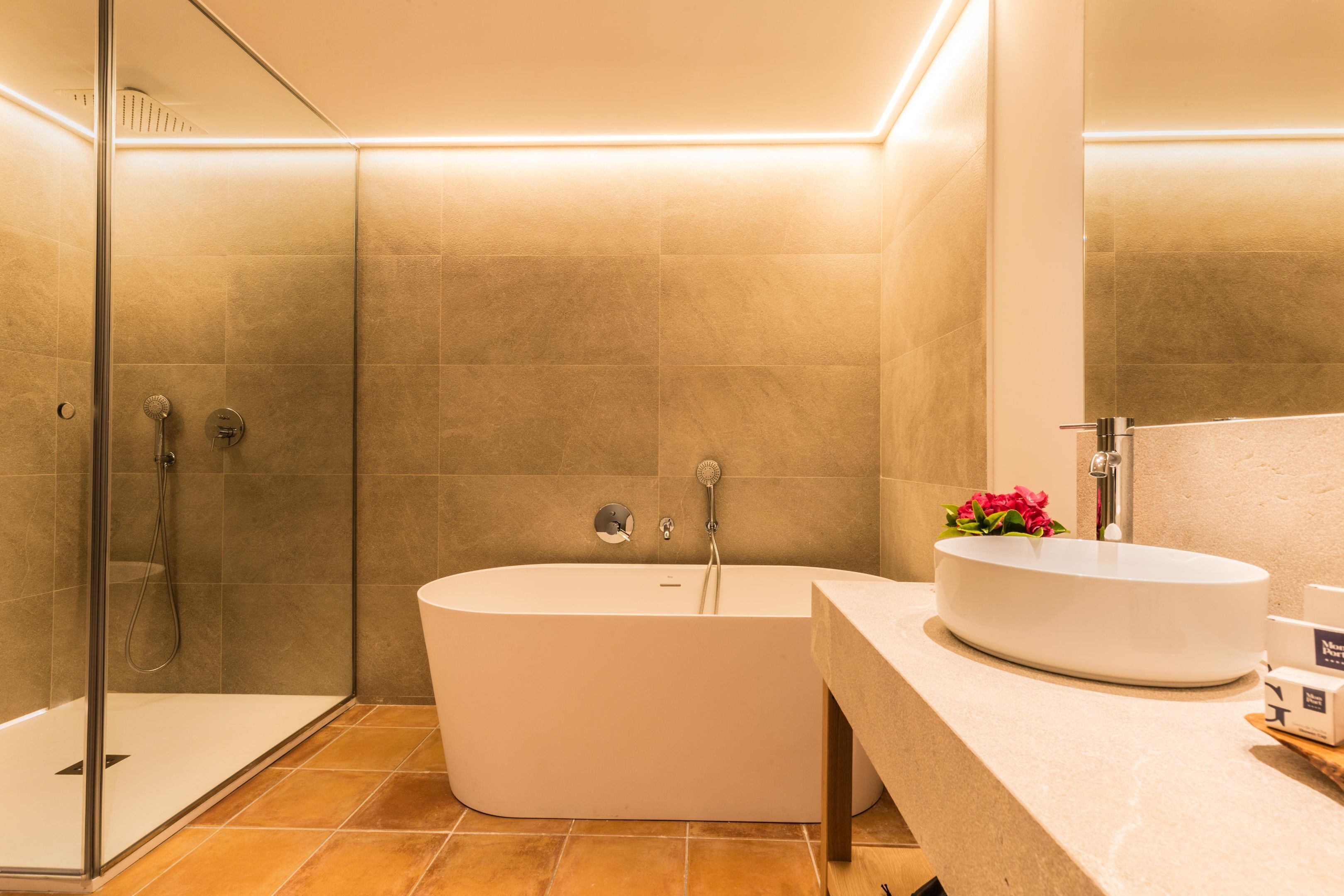A modern bathroom with a freestanding bathtub, a glass-enclosed shower, and a vanity with a sink and mirror.