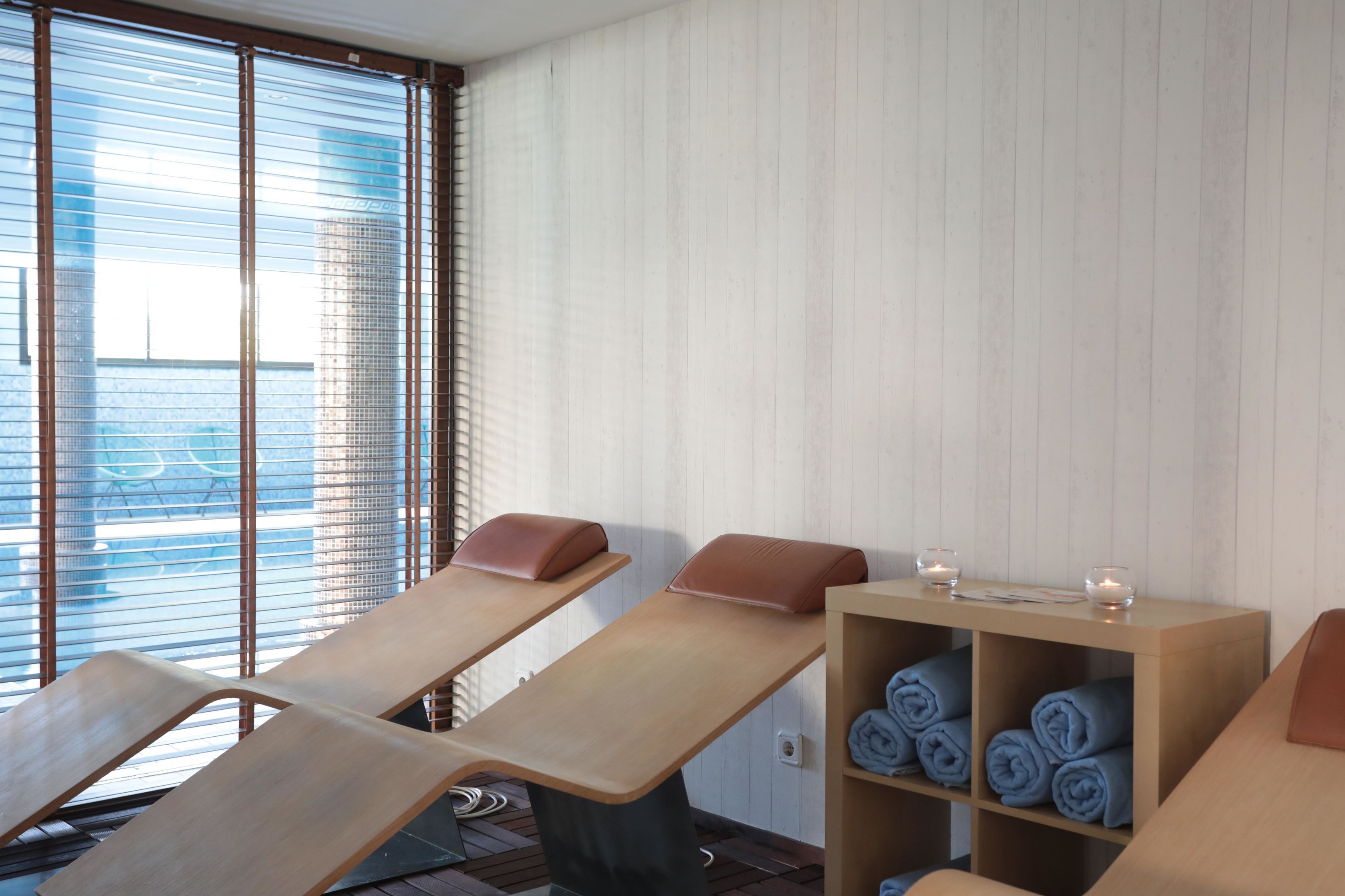 A spa room with massage tables, towels, and candles.