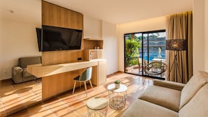 Un salon moderne avec un bureau en bois, un téléviseur à écran plat, un canapé et un balcon donnant sur la piscine.