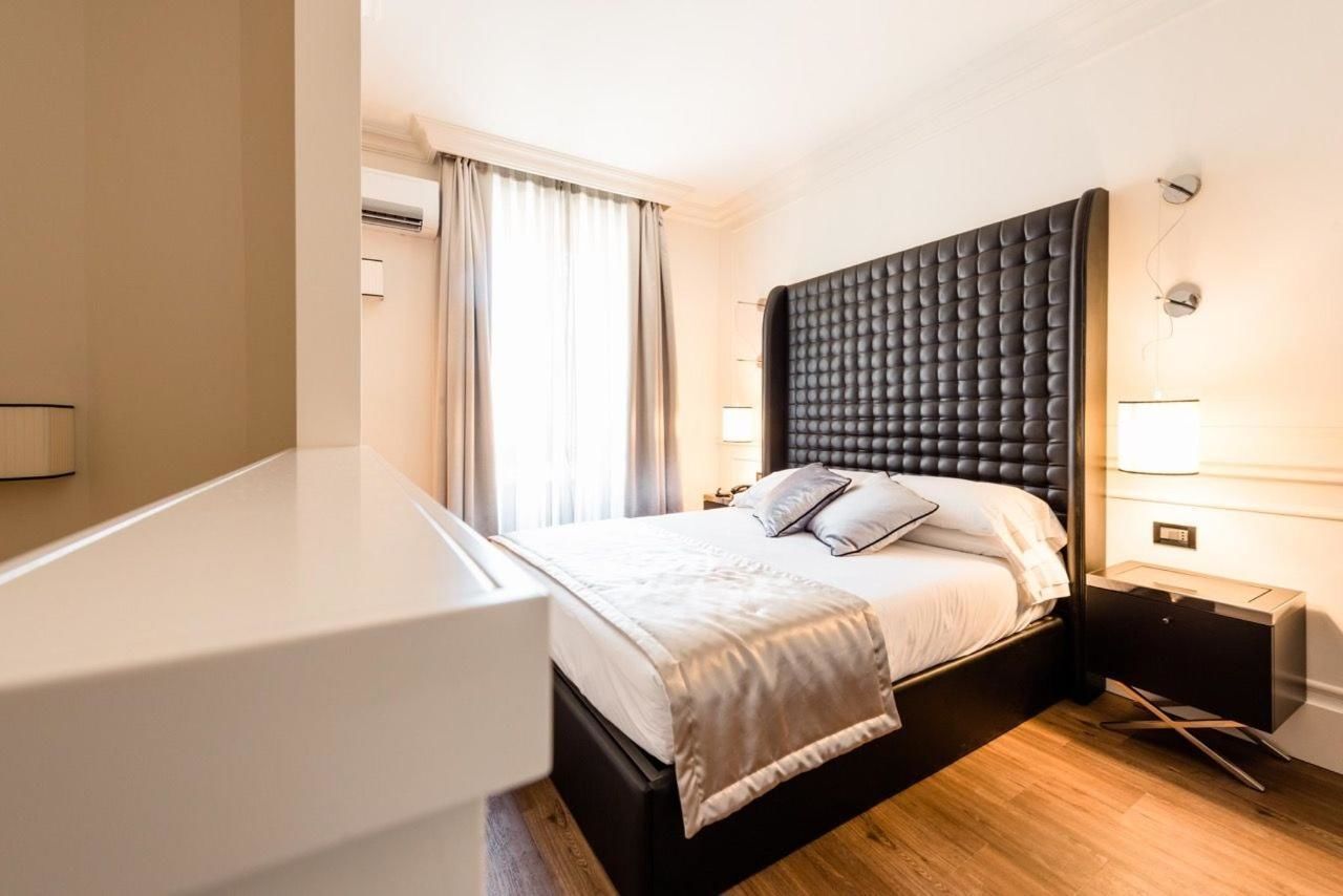 Una habitación de hotel moderna con una cama grande, lámparas de noche y suelo de madera.