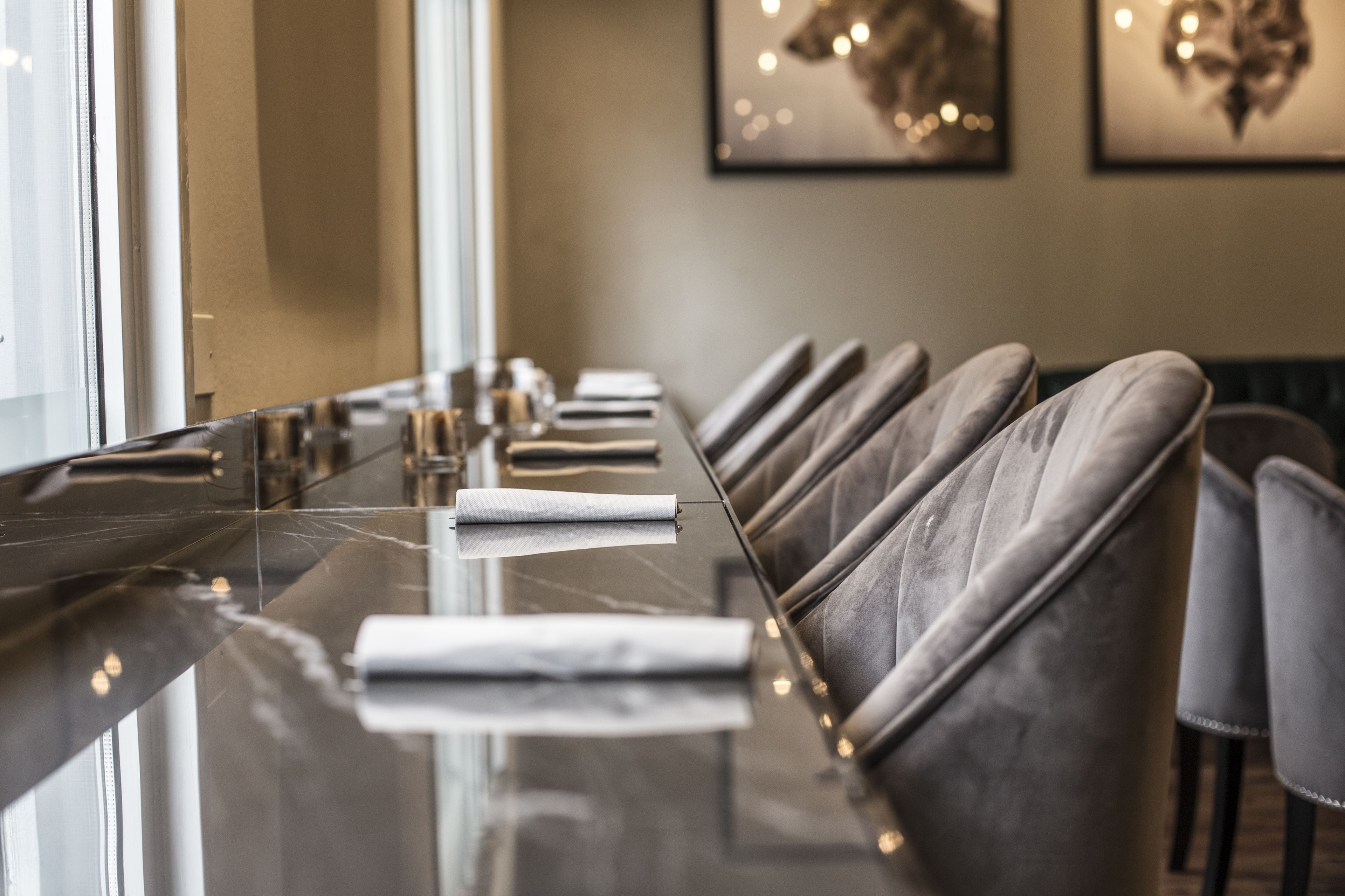 A long, reflective marble table with leather chairs in a modern dining area.
