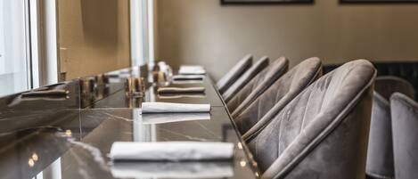 A long, reflective marble table with leather chairs in a modern dining area.