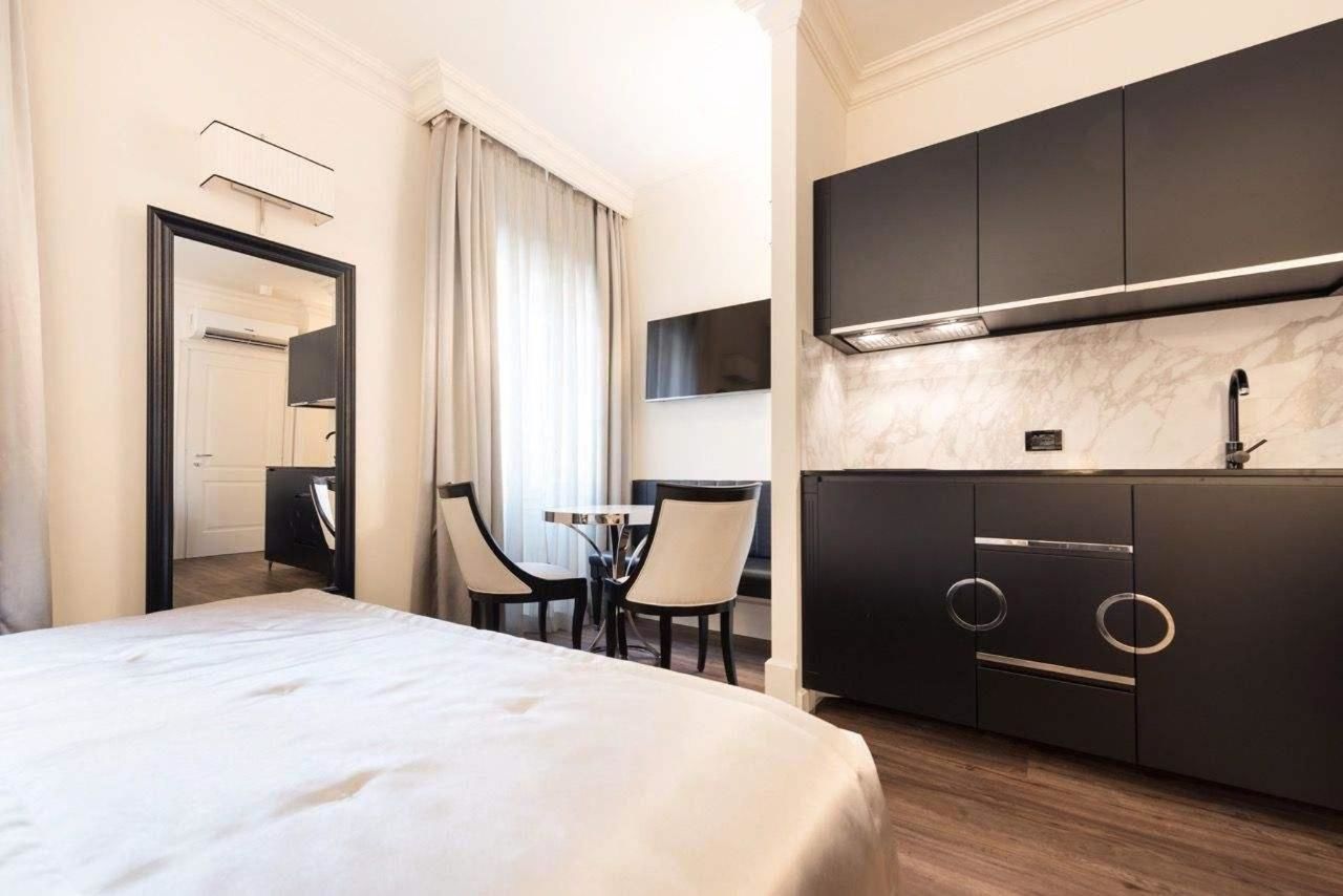 Een hotelkamer met een bed, een bureau, stoelen, een televisie en een moderne keukenhoek.
