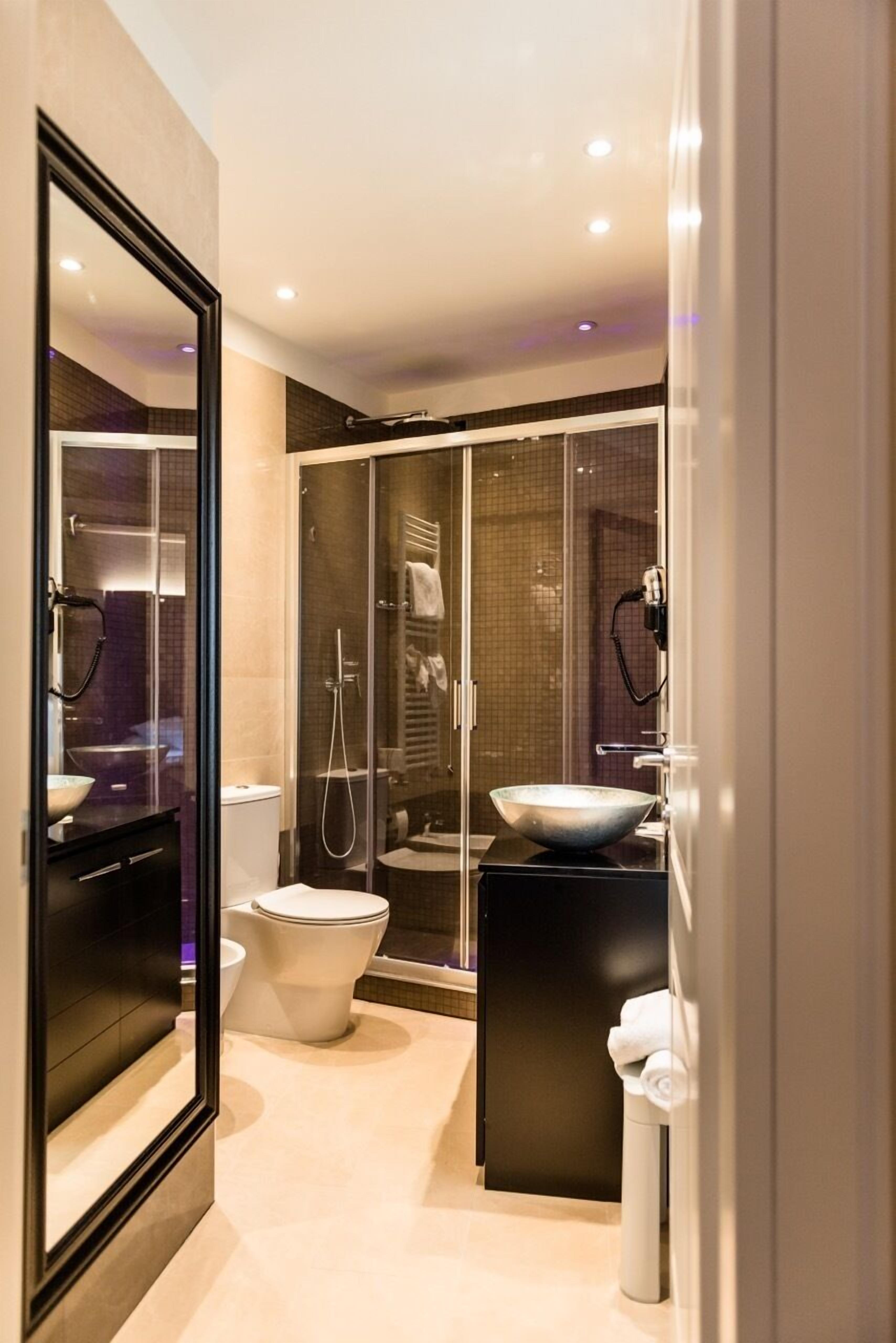 A modern bathroom with a glass-enclosed shower, a large mirror, and a black vanity.