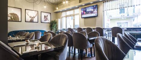 Un ristorante con sedie in pelle, un tavolo nero e una televisione appesa al muro.