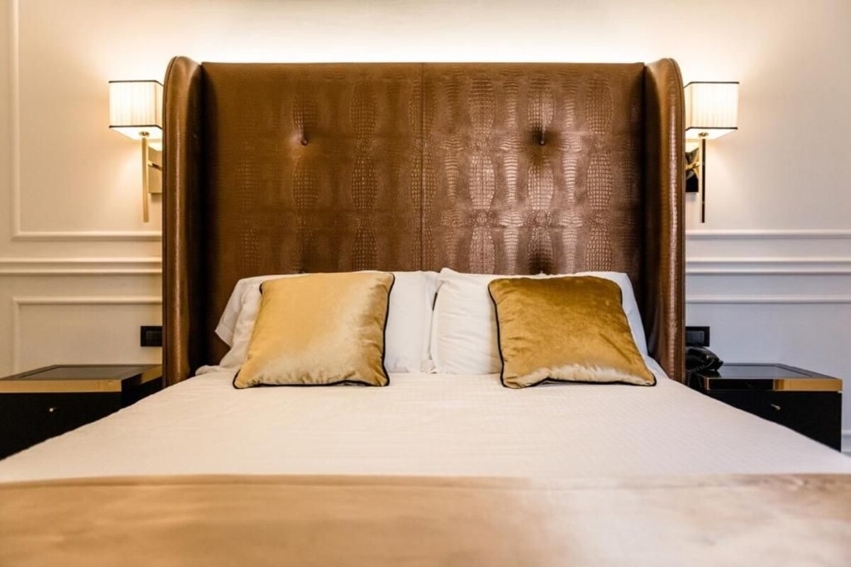 A bed with a tufted headboard, two bedside lamps, and two pillows.