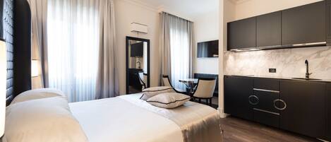 Une chambre d’hôtel moderne dotée d’un grand lit, d’un coin repas séparé et d’un espace cuisine.