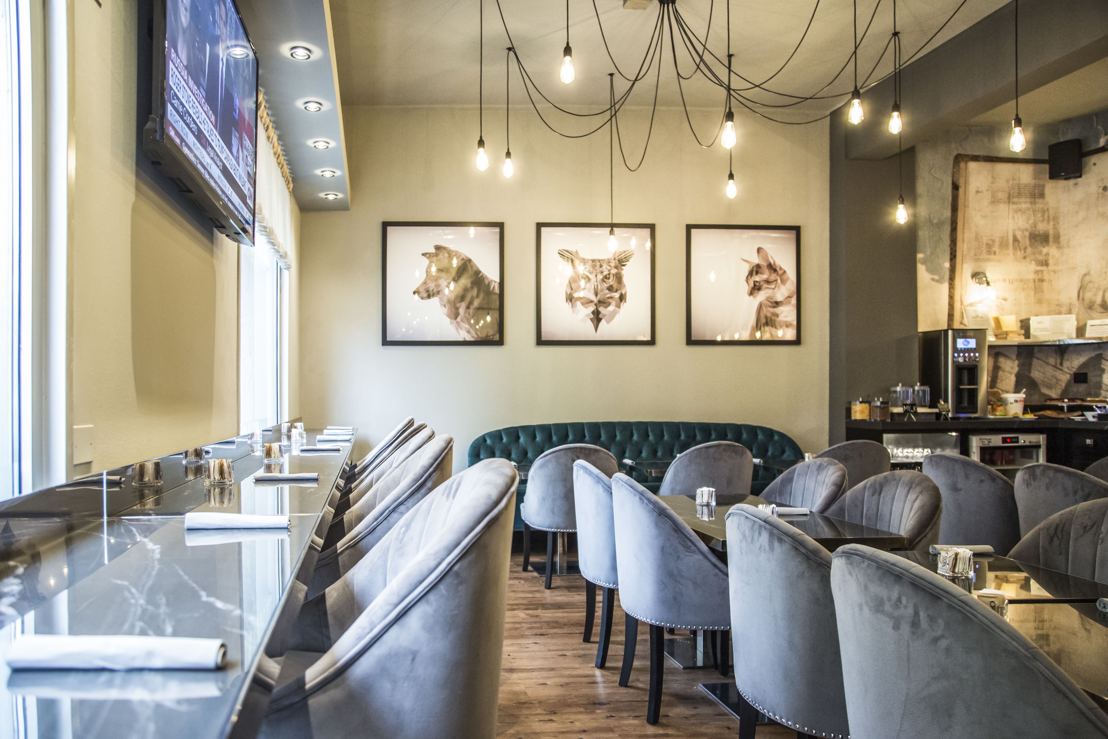 Un restaurante moderno con una barra larga, asientos acolchados y cuadros con motivos de animales en la pared.