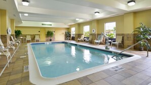 An indoor swimming pool with clear water, surrounded by lounge chairs and potted plants. - Hampton Inn Utica (Utica)