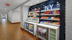 A corridor with a NY-themed snack display and refrigerated beverage coolers. - Hampton Inn Utica (Utica)