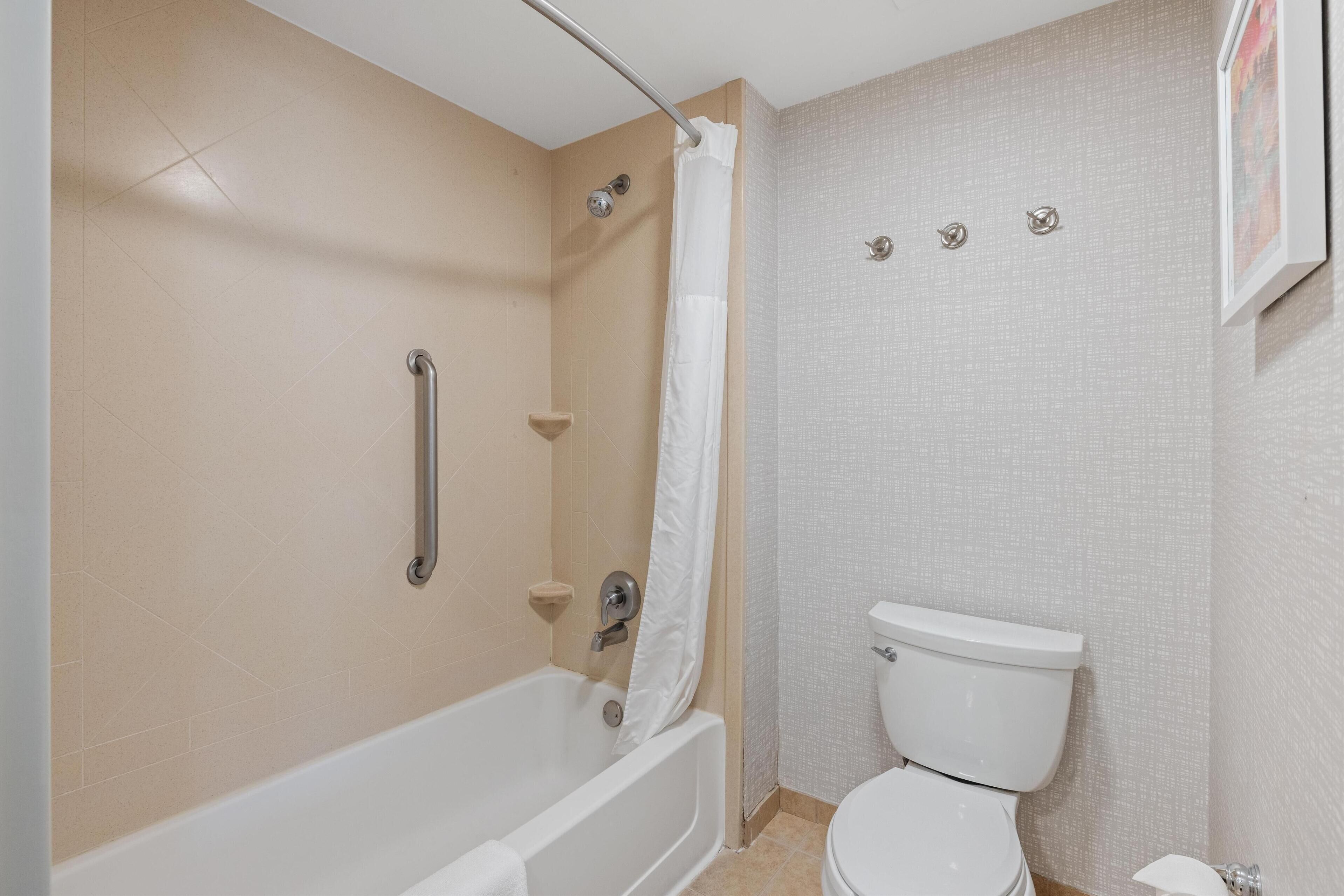 Un baño con bañera, inodoro y cortina de ducha.