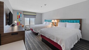 Una habitación de hotel con dos camas, un escritorio, un televisor y una ventana con persianas.
