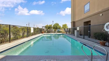 A rectangular swimming pool with a metal railing, surrounded by a fence, and a sign indicating a depth of 5 feet 1.5 meters.