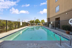 A rectangular swimming pool with a metal railing, surrounded by a fence, and a sign indicating a depth of 5 feet 1.5 meters.