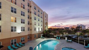 Un hotel con piscina, zona de estar exterior y vistas al atardecer.