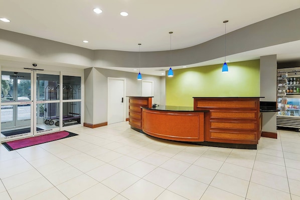 A reception area with a wooden reception desk, glass doors leading outside, and a green wall.