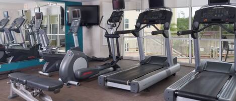 A gym with treadmills, elliptical machines, and a weight bench.