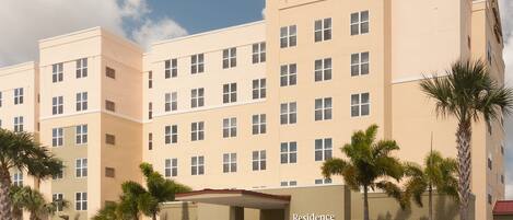 Un hotel de varios pisos con fachada color crema, múltiples ventanas y un letrero que dice "Residence Inn Marriott".