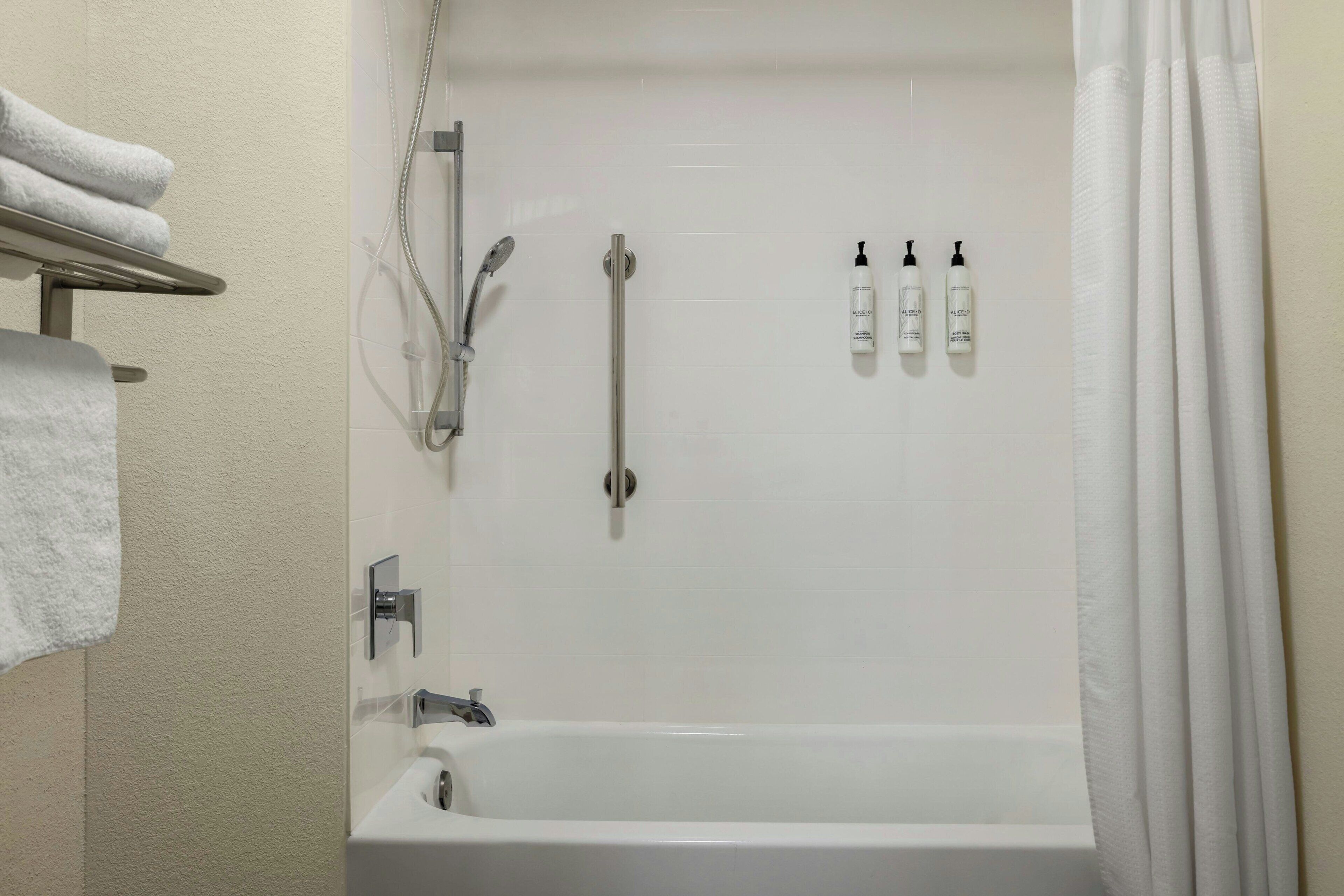 A bathroom with a bathtub, a shower, and three bottles of shampoo.