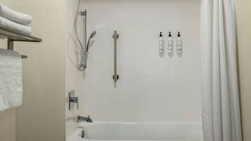 A bathroom with a bathtub, a shower, and three bottles of shampoo.