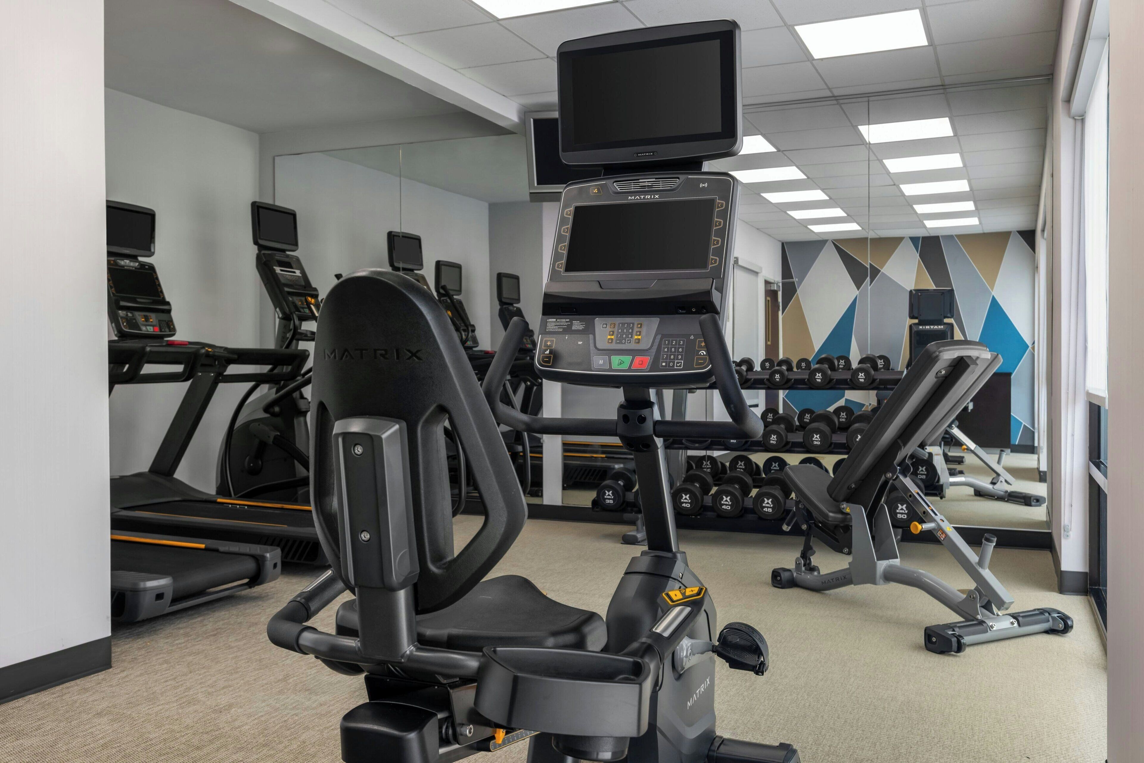 Un gimnasio con cintas de correr, elípticas y equipo de levantamiento de pesas.