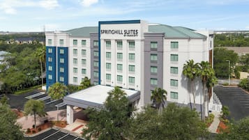 A multi-story hotel with a flat roof, surrounded by greenery and a parking lot.