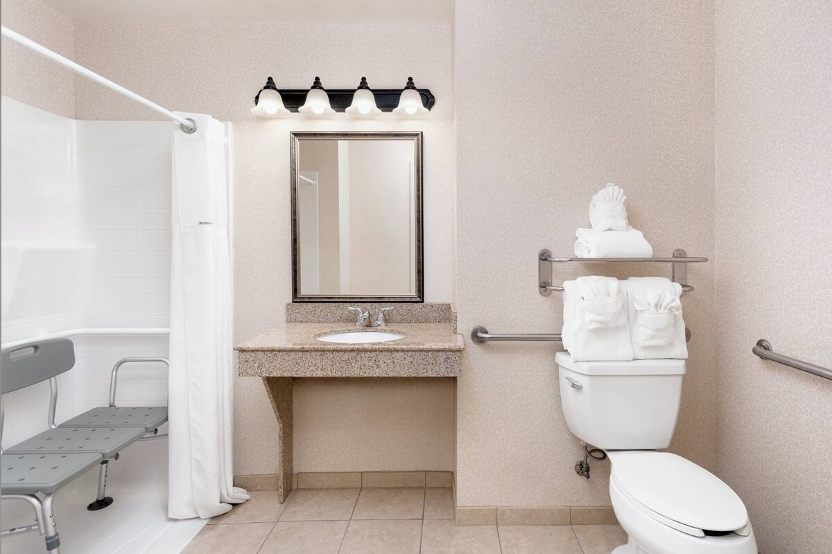 Une salle de bain équipée d’une douche, d’un lavabo, de toilettes et d’un banc.