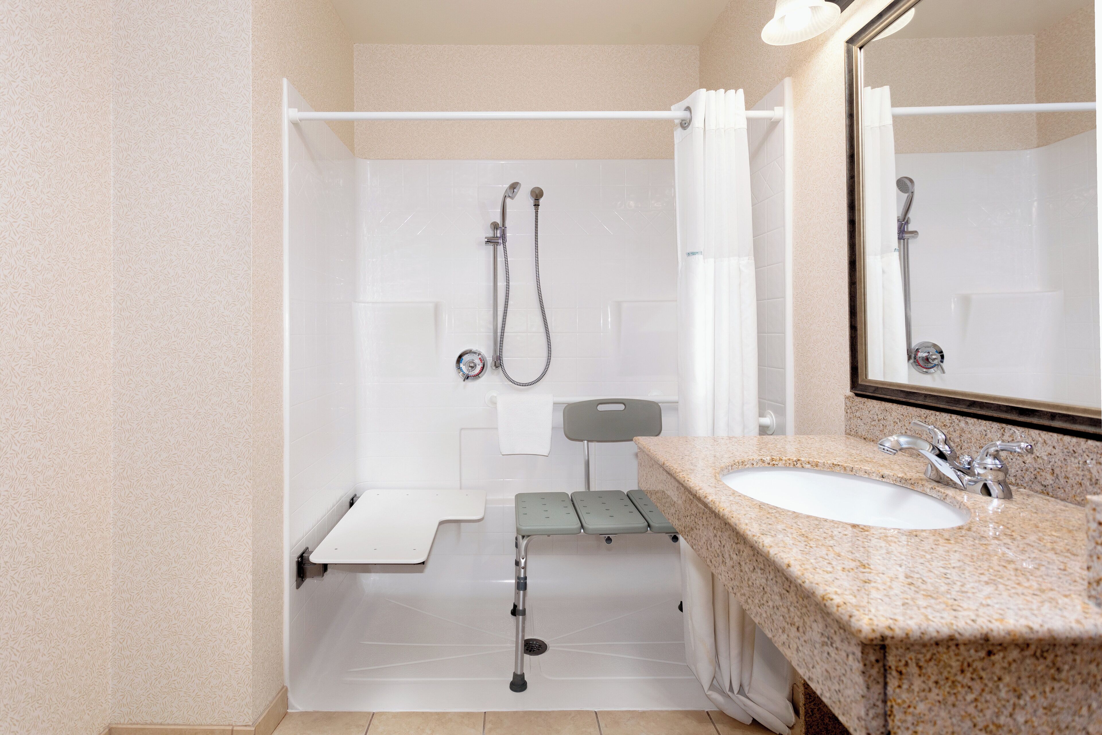 A bathroom with a shower, a sink, and a mirror.