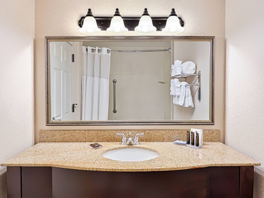 A bathroom with a large mirror, a sink, and a towel rack with towels.