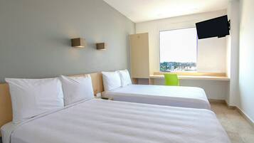 Habitación de hotel con dos camas, un televisor montado en la pared y una ventana con vista a la ciudad.