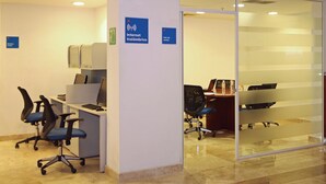 Un espacio de oficina con cubículos, computadoras y sillas de escritorio. Se observan carteles que indican acceso a Internet y una sala de reuniones.