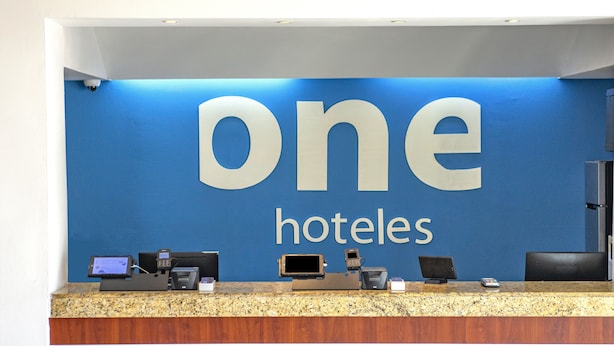 Un mostrador de recepción con una pared azul y el texto "one hotels" en letras grandes.