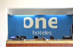 Un mostrador de recepción con una pared azul y el texto "one hotels" en letras grandes.