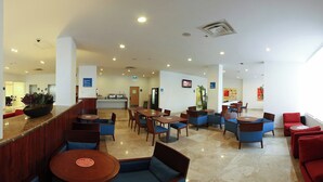 Un vestíbulo de hotel con zonas de estar, una recepción e indicación de salida.
